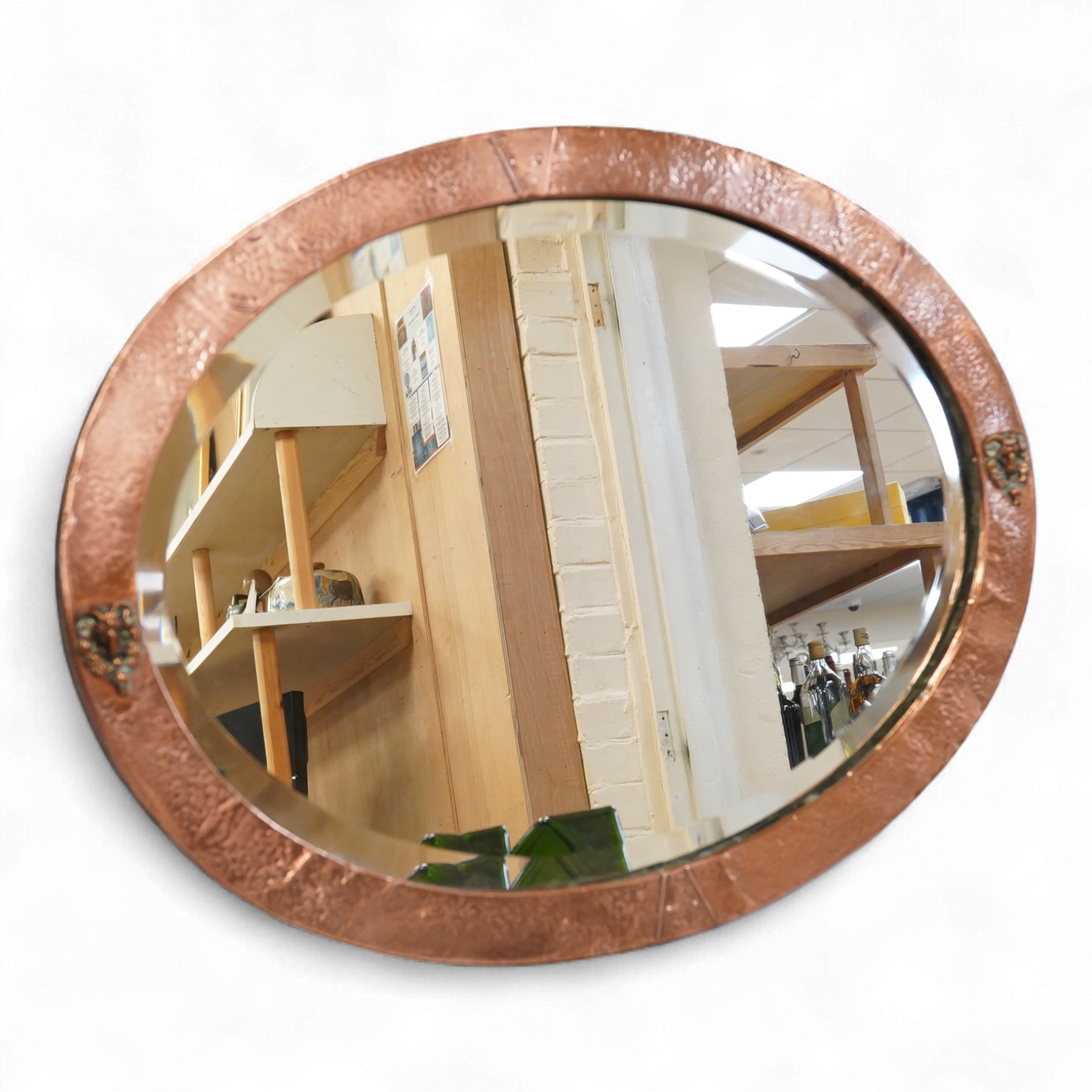 An oval late 19th century hammered copper wall mirror with rams head cartouches, 65cm wide